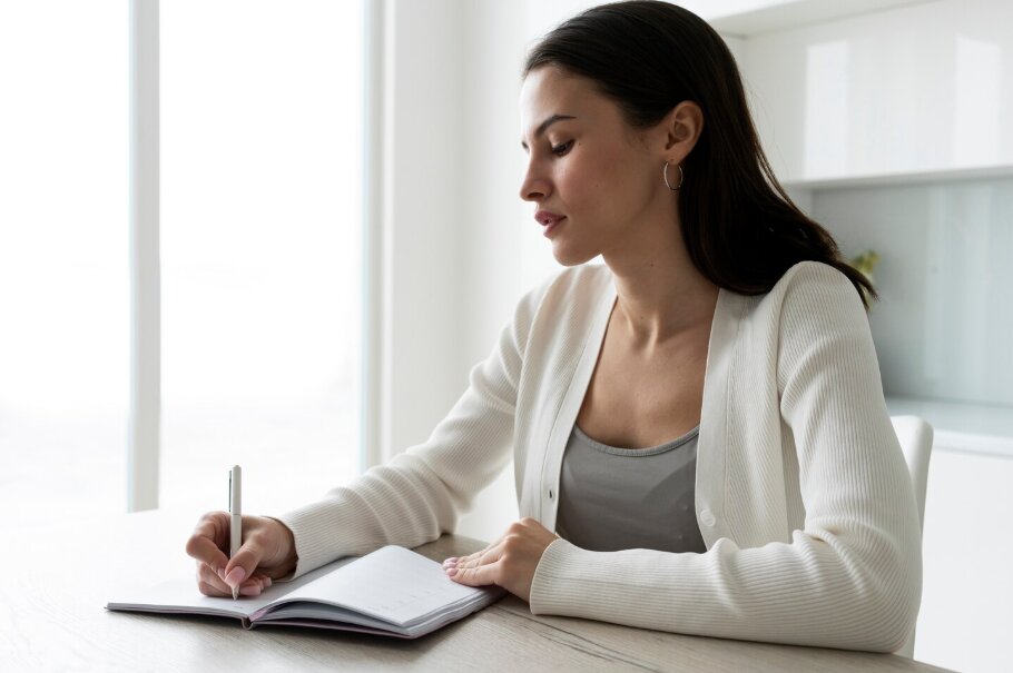Medium shot woman writing in notebook